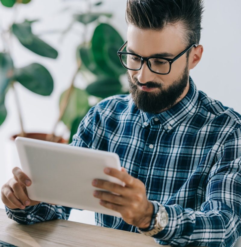 bearded young seo using tablet at workplace